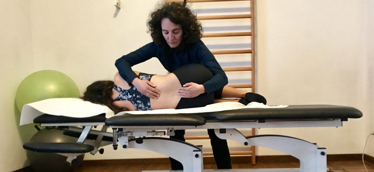 Fisioterapista esegue un trattamento manuale sulla schiena di una paziente nello Studio Physioup